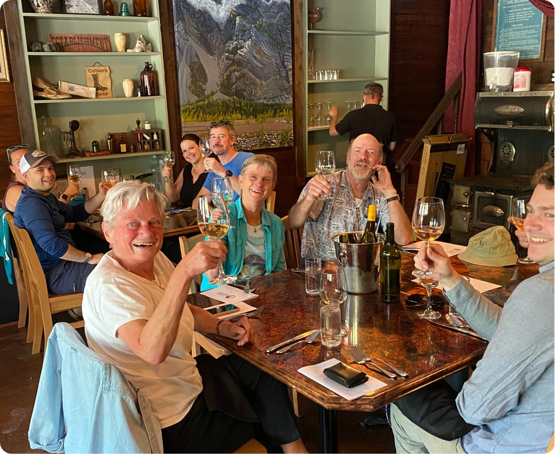 Group of people toasting with wine at a rustic table inside a cozy restaurant