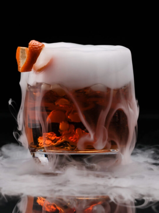 cocktail with smoky overflow and orange garnish