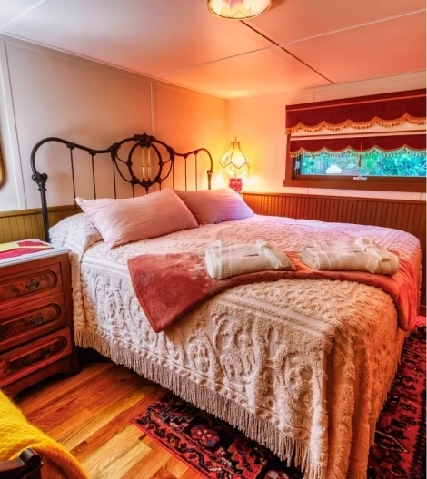 Cozy bedroom with an iron-frame bed, textured bedding, warm lighting, and a colorful rug