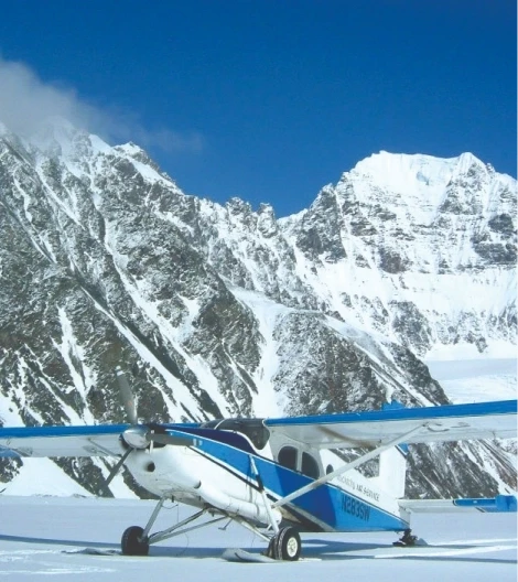 Small airplane on a snowy mountainous landscape under clear blue skies